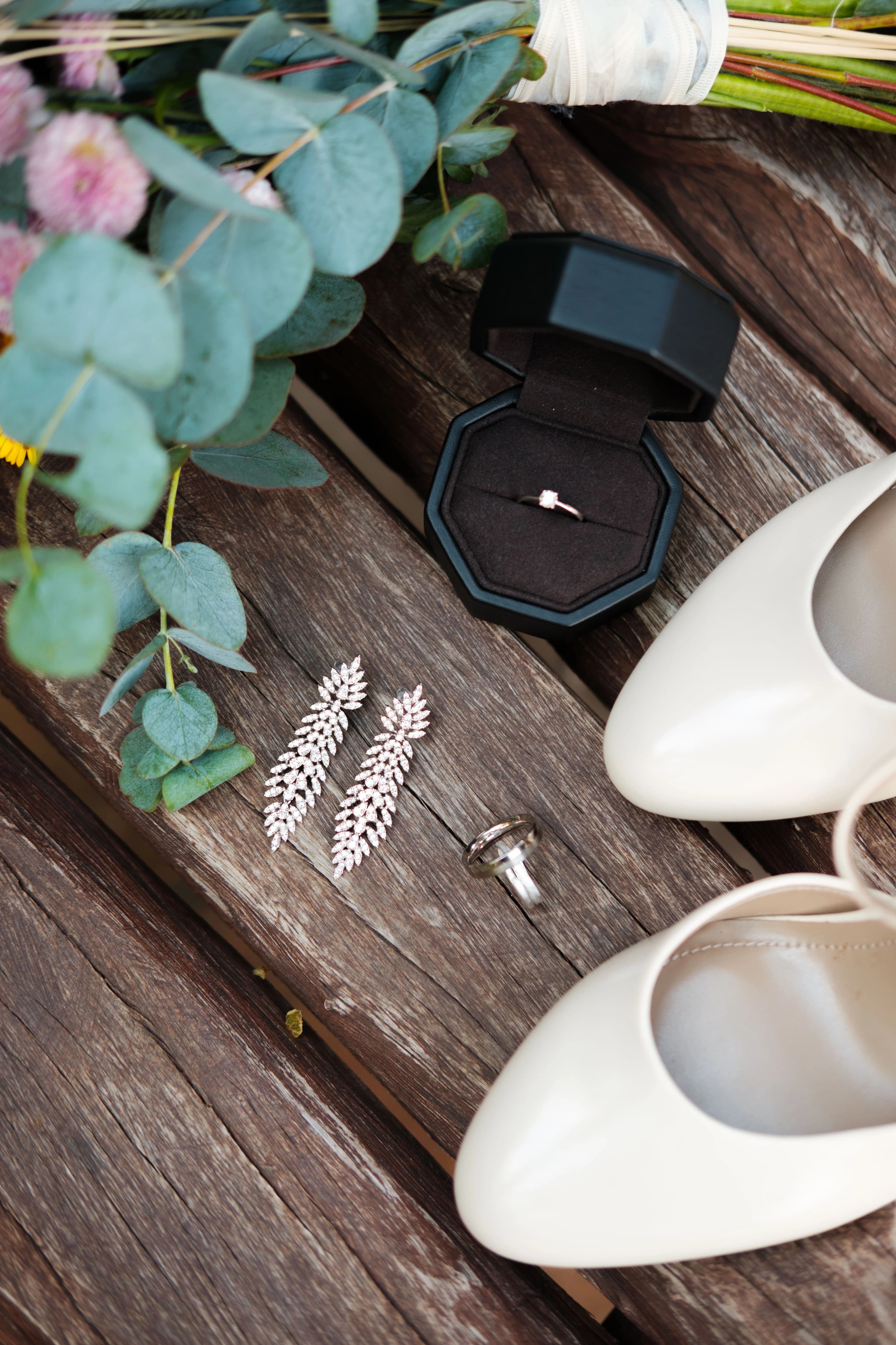 Detalle de anillos de boda, tacones y accesorios de novia en un entorno natural en Girón.